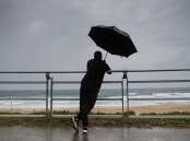 Some shelter under the rain at Cronulla. Sydney is copping a drenching on Friday. Picture by John Veage
